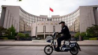 A man wears a protective mask as he rides past the The People’s Bank of China in Beijing.