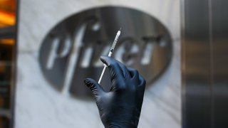 A syringe is seen by the logo of Pfizer’s headquarter in Manhattan, New York City, United States on November 19, 2020.