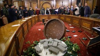 People shout as they broke into the government building protesting against an agreement to halt fighting over the Nagorno-Karabakh region, in Yerevan, Armenia, Tuesday, Nov. 10, 2020. Armenian Prime Minister Nikol Pashinian said on Facebook that calling an end to the fight was "extremely painful for me personally and for our people." Soon after the announcement, thousands of people streamed to the main square in the Armenian capital Yerevan to protest the agreement, many shouting "We won't give up our land." Some of them broke into the main government building, saying they were searching for Pashinian, who apparently had already departed.