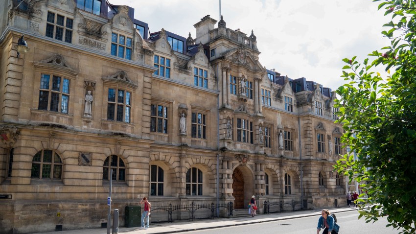 Pedestrians and a cyclist pass Oriel College, where a statue of Cecil Rhodes stands above an entrance, at the University of Oxford in Oxford, U.K., on Monday, July 20, 2020.