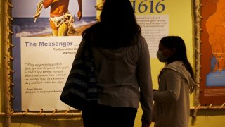 Visitors to the Pilgrim Monument and Provincetown Museum pause to examine a new exhibit in Provincetown, MA on Aug. 27, 2020. The new exhibit explores the early interactions between the Pilgrims and the Wampanoag tribe.