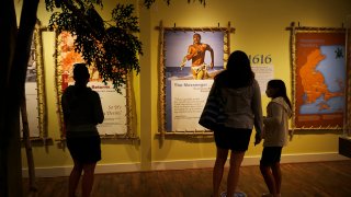 Visitors to the Pilgrim Monument and Provincetown Museum pause to examine a new exhibit in Provincetown, MA on Aug. 27, 2020. The new exhibit explores the early interactions between the Pilgrims and the Wampanoag tribe.