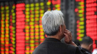 An investor looks at an electronic board showing stock information at a brokerage house in Nanjing, Jiangsu province, China.