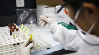 File photo: a health worker wearing a protective mask works in a lab during clinical trials for a Covid-19 vaccine at Research Centers of America in Hollywood, Florida.