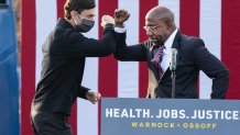 Georgia Democratic Senate candidates Raphael Warnock (R) and Jon Ossoff (L) bump elbows during a "It's Time to Vote" drive-in rally on December 28, 2020 in Stonecrest, Georgia.