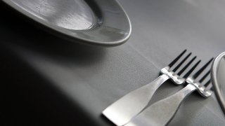 A place setting at a restaurant, complete with cutlery, tablecloth and plate.