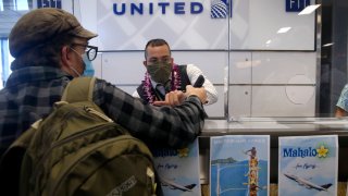 United Airlines gate attendant Daniel Chester assists a passenger before a flight to Honolulu at SFO