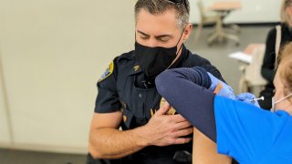 A San Diego Police Department Sergeant receives the first dose of the Pfizer vaccine at the Sharp Memorial Hospital Vaccination Clinic