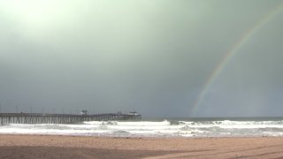 A rainbow forms over the Imperial Beach Pier during a storm