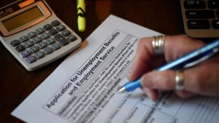 In this photo illustration, a person files an application for unemployment benefits. (Photo by Olivier DOULIERY / AFP) (Photo by OLIVIER DOULIERY/AFP via Getty Images)