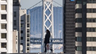 A pedestrian wearing a protective mask crosses California Street in San Francisco, California, U.S., on Tuesday, Dec. 29, 2020.