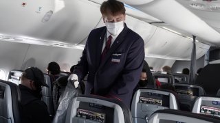 A flight attendant gathers trash on a flight aboard a Boeing 737 Max from Dallas Fort Worth Airport to Tulsa, Oklahoma, December 2, 2020.