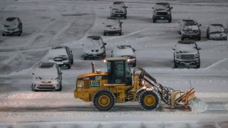 Crews clean snow from a car parking lot at O’Hare International Airport in Chicago, Illinois, on January 26, 2021. (Photo by KAMIL KRZACZYNSKI / AFP) (Photo by KAMIL KRZACZYNSKI/AFP via Getty Images)