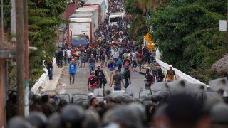 Honduran migrants, top, stand next to cargo trucks as they confront Guatemalan soldiers and police