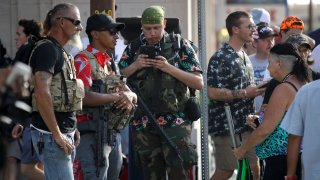 gun-carrying men wearing Hawaiian print shirts associated with the boogaloo movement watch a demonstration near where President Trump had a campaign rally in Tulsa, Okla