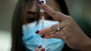 A pharmacist dilutes the Pfizer COVID-19 vaccine while preparing it to administer to staff and residents at the Goodwin House Bailey's Crossroads, a senior living community in Falls Church, Virginia, on December 30, 2020. (Photo by Brendan Smialowski / AFP) (Photo by BRENDAN SMIALOWSKI/AFP via Getty Images)