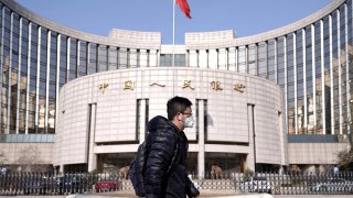 A man wearing a mask walks past the headquarters of the People’s Bank of China, the central bank, in Beijing, China, as the country is hit by an outbreak of the new coronavirus, February 3, 2020.