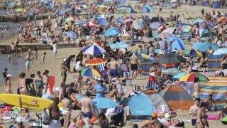 People gather on the beach during hot weather in Bournemouth, southern England, Sunday Aug. 9, 2020. Many Britons are set to bask in another hot day, with clear skies and hot temperatures predicted to continue.
