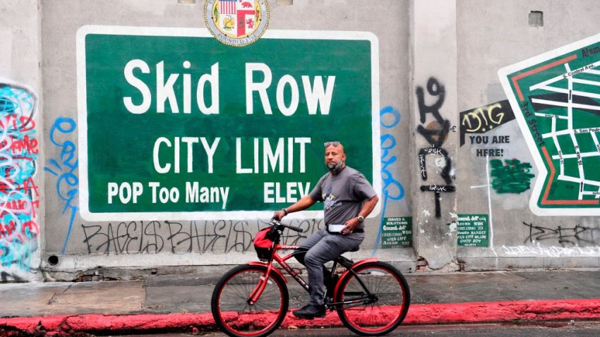 A cyclist rides past a Skid Row sign in Los Angeles, California on February 1, 2021. – The federal judge overseeing attempts to resolve the homeless situation has called for an urgent meeting to discuss worsening conditions and the poor official response. Combined now with the coronaviruspandemic and worsening mental health and substance abuse issues, US District Judge David Carter  who toured Skid Row last week likened the situation to “a significant natural disaster in Southern California with no end in sight.” (Photo by Frederic J. BROWN / AFP) (Photo by FREDERIC J. BROWN/AFP via Getty Images)