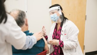 famrmacéutica administrando la vacuna contra el covid-19 a un paciente.