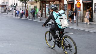 A distributor of Deliveroo is seen riding his bike with a package with food on a street on July 31, 2019 in Madrid, Spain.