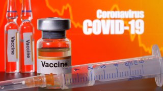 Small bottles labelled with “Vaccine” stickers stand near a medical syringe in front of displayed “Coronavirus COVID-19” words in this illustration taken April 10, 2020.