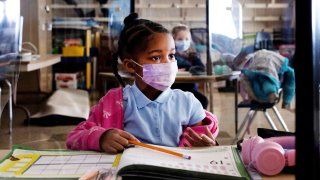 a girl wearing a face mask looks on at her desk inside a Philadelphia school.