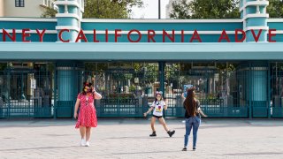 Visitors to the Disneyland Resort take pictures in front of Disney California Adventure Park in Anaheim, CA, on Thursday, October 22, 2020.