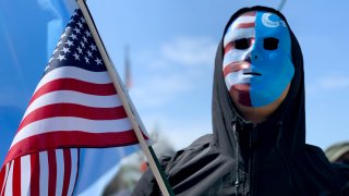A demonstrator, wearing a mask, holds a US flag during a protest against Chinas human rights abuses against Uighur Muslims in Xinjiang province, calling on U.S. government to take action against Beijing, on April 06, 2019 in Washington, United States.