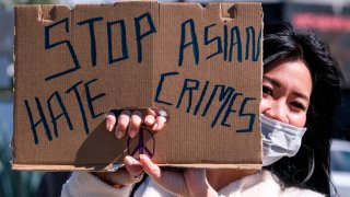 A demonstrator wearing a face mask and holding a sign takes part in a rally to raise awareness of anti-Asian violence, near Chinatown in Los Angeles, California, on February 20, 2021. – The rally was organized in part in response to last month’s fatal assault of Vicha Ratanapakdee, an 84-year-old immigrant from Thailand, in San Francisco. (Photo by RINGO CHIU / AFP) (Photo by RINGO CHIU/AFP via Getty Images)