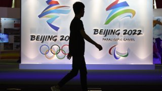 In this 2018 file photo, a visitor walks past logos of the upcoming Beijing 2022 Winter Olympic and Paralympic Games during the Beijing Olympic Expo marking the 10th anniversary of the 2008 Olympic Games, in Beijing.
