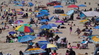 People enjoy the hot weather on Santa Monica Beach in Santa Monica, California, March 31, 2021. Half of the state's nearly 40 million people are now in the state's second-least restrictive orange tier amid low coronavirus case rates and increased vaccinations. Health officials in California and across the country are urging caution because of a troubling rise in new cases of COVID-19.