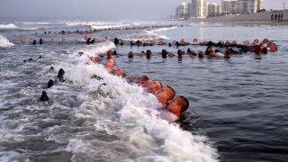 FILE – This May 4, 2020, photo provided by the U.S. Navy shows SEAL candidates participating in “surf immersion” during Basic Underwater Demolition/SEAL (BUD/S) training at the Naval Special Warfare (NSW) Center in Coronado, Calif. U.S. Navy SEALs are undergoing a major transition to improve leadership and expand their commando capabilities.