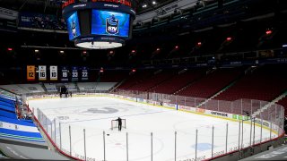 VANCOUVER, BC - MARCH 31: A rink attendant pushes a game net off the ice after the NHL game between the Calgary Flames and the Vancouver Canucks was postponed due to a positive COVID test result of a player at Rogers Arena on March 31, 2021 in Vancouver, British Columbia, Canada.