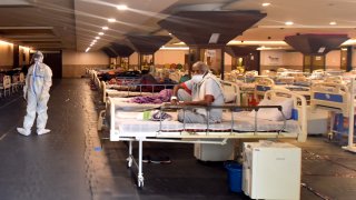 In this April 12, 2021, file photo, medical staff in PPE coveralls attend to patients housed in the Shehnai Banquet Hall COVID-19 care centre attached to LNJP Hospital in New Delhi, India. Amid resurgence in COVID-19 cases and hospitals running out of beds, the Delhi government has begun setting up facilities for coronavirus patients at alternative places like banquet halls.