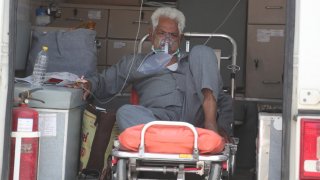 A COVID-19 patient waits inside an ambulance to be attended to and admitted into a dedicated COVID-19 government hospital in Ahmedabad, India, Thursday, April 22, 2021. A fire killed 13 COVID-19 patients in a hospital in western India early Friday as an extreme surge in coronavirus infections leaves the nation short of medical care and oxygen. India reported another global record in daily infections for a second straight day Friday, adding 332,730 new cases. The surge already has driven its fragile health systems to the breaking point with understaffed hospitals overflowing with patients and critically short of supplies.