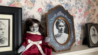 A doll sits in front of photos of Lizzie Borden in her former home.