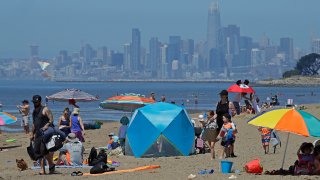 people congregate on Robert W. Crown Memorial State Beach with the San Francisco skyline as a backdrop