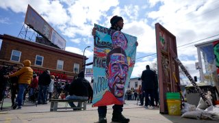 A man holds a sign at George Floyd Square, in Minneapolis