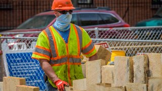 Construction workers wearing protective face masks on site.