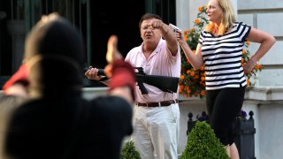 Armed homeowners Mark T. and Patricia N. McCloskey stand in front their house as they confront protesters marching to St. Louis Mayor Lyda Krewson's house on June 28, 2020.