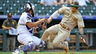 Manny Machado #13 of the San Diego Padres slides into a tag by Elias Diaz #35 of the Colorado Rockies for an out at home plate to end the fourth inning of a game at Coors Field on June 16, 2021 in Denver, Colorado.