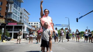 Starr Patterson stood with a child as they raised their first in the intersection of West Lake Street and Girard Friday afternoon as protesters shut down traffic near the site of the shooting death of Winston Smith in Uptown.