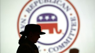 Republican Party members are silhouetted against the Republican National Committee (RNC) logo at the RNC annual winter meeting at a hotel in Washington.