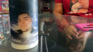 A candle in the foreground with someone in the background sitting at the table.