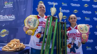 Winners Joey Chestnut and Michelle Lesco pose with their championship belts and trophies at the Nathan's Famous Fourth of July International Hot Dog-Eating Contest in Coney Island's Maimonides Park