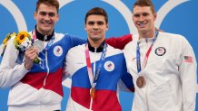 Gold medalist Evgeny Rylov, centre, of the Russian Olympic Committee stands with compatriot and silver medalist Kliment Kolesnikov, left, and bronze medalist Ryan Murphy of the United States after the men's 100-meter backstroke final at the 2020 Olympics on July 27, 2021, in Tokyo, Japan.