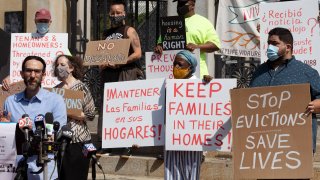 People from a coalition of housing justice groups hold signs protesting evictions