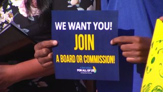 A sign is held encouraging San Diego youngsters to join the city's revived Youth Commission.