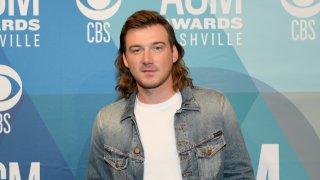 Morgan Wallen stands in a white shirt and jean jacket.